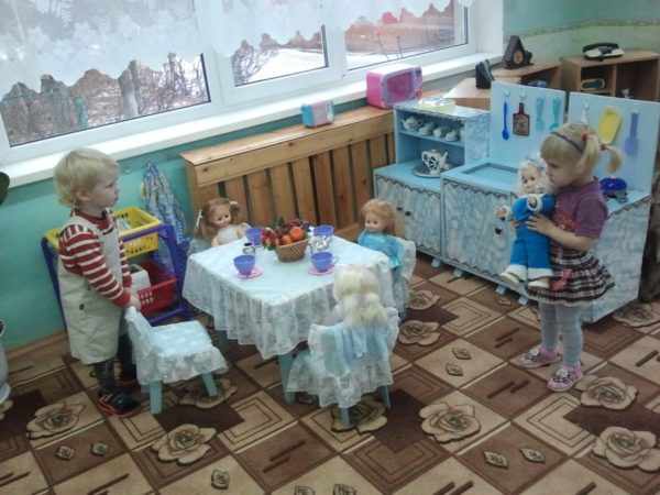 Двое детей играют в чаепитие с куклами