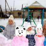 Три девочки стоят рядом с медведем и куклой, сделанными из снега