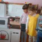 Трое детей стоят рядом с макетом-декорацией для спектакля «Русская печь»