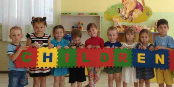 Дети с большими пазлами в руках со словом «children»
