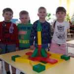 Четыре ребёнка стоят рядом с построенной из конструктора ракетой
