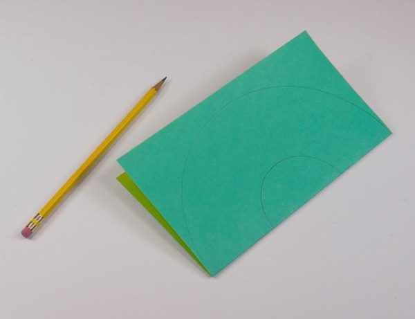 Карандаш и сложенный пополам лист бумаги с изображением кругов
