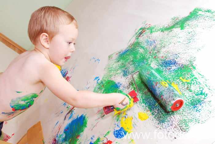 Ребенок рисует на стене валиком