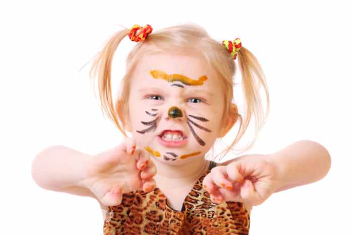 Маленькая девочка в костюме тигра рычит