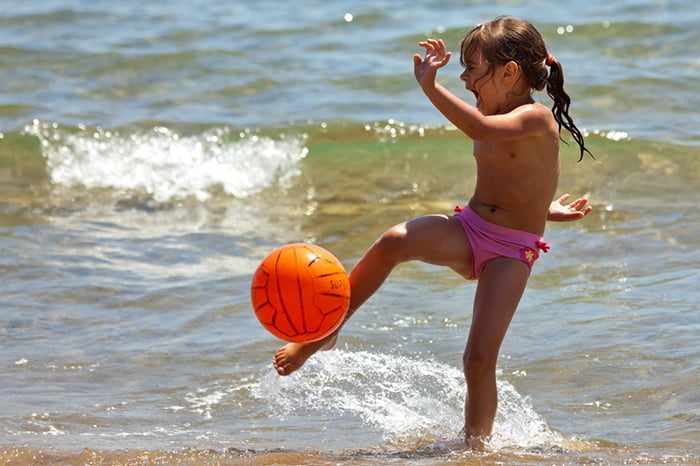 Девочка играет в мяч на берегу моря