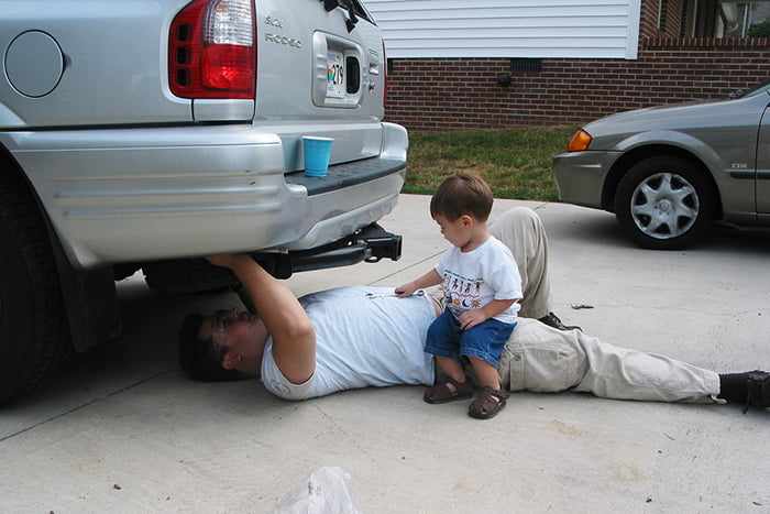 Малыш смотрит, как папа чинит машину