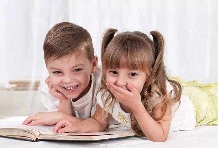 Дети читают книжку и смеются