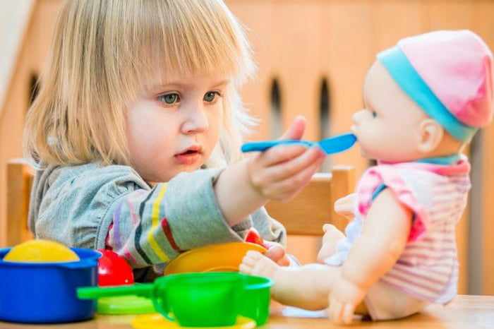 Маленькая девочка играет с куклой
