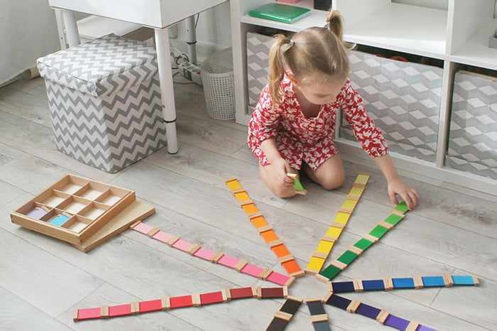 Девочка играет с разноцветными табличками Монтессори