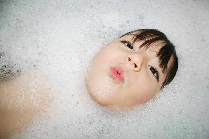 Девочка ныряет в ванне с пеной