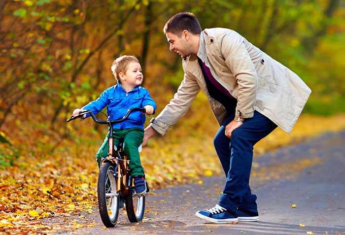 Папа учит сына кататься на велосипеде
