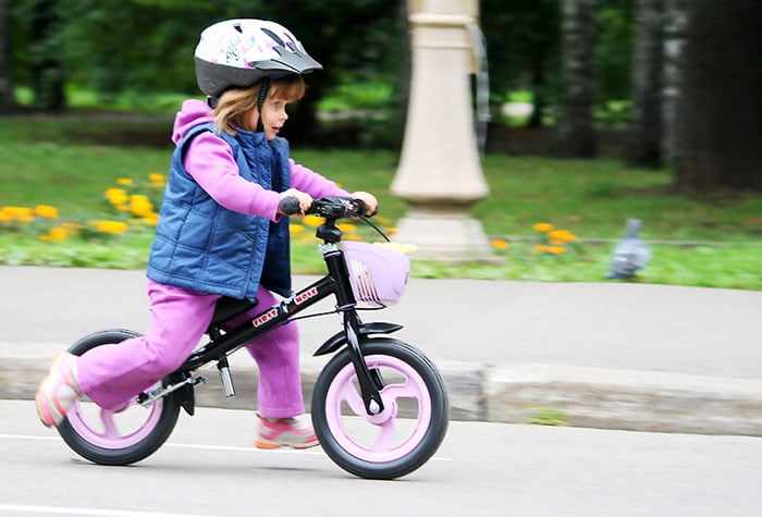 Девочка на маленьком двухколесном велосипеде