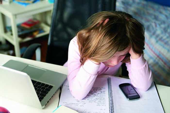 Девочка грустит рядом с компьютером и телефоном 