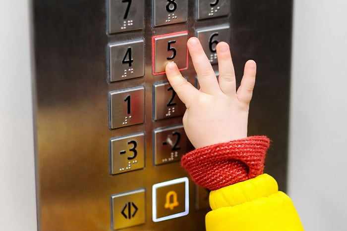 Ребенок нажимает кнопку в лифте