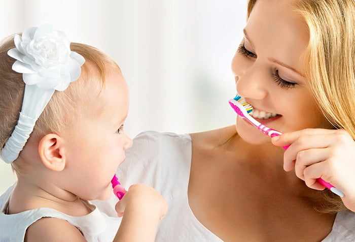 Маленькая девочка учится чистить зубки