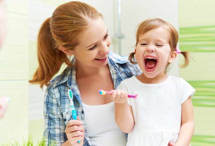 Девочка с мамой чистят зубы