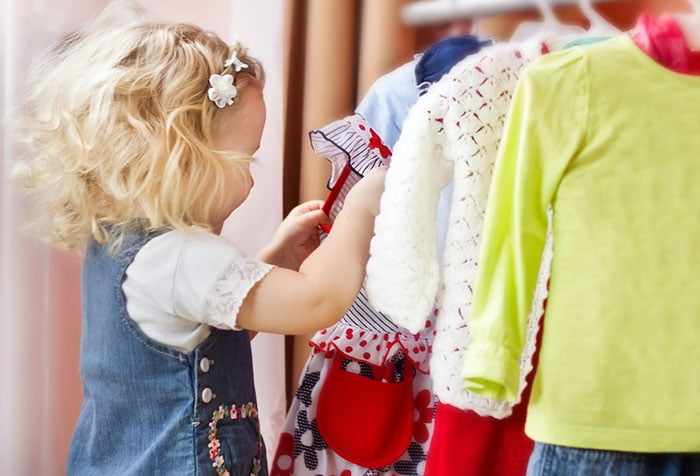 Маленькая девочка выбирает одежду