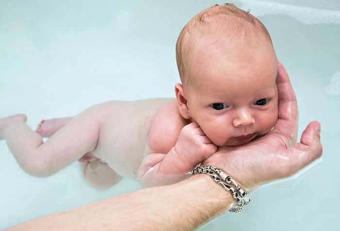 Новорожденный плавает в ванне