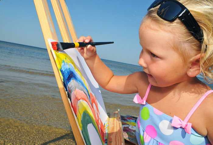 Девочка рисует радугу на берегу моря