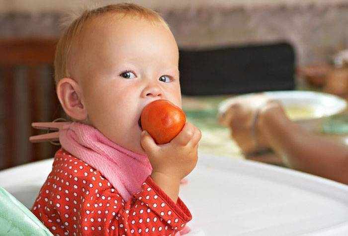Ребенок грызет помидор