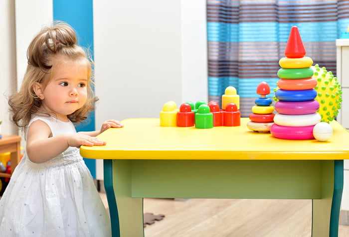 Девочка у стола с развивающими игрушками