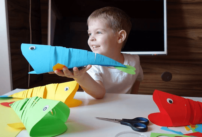 Ребенок вырезает китов из цветной бумаги