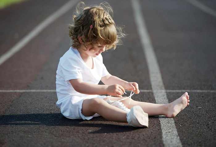 Ребенок пытается завязать шнурки