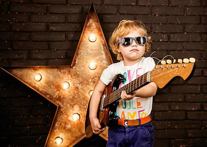 Ребенок с гитарой изображает рок-звезду