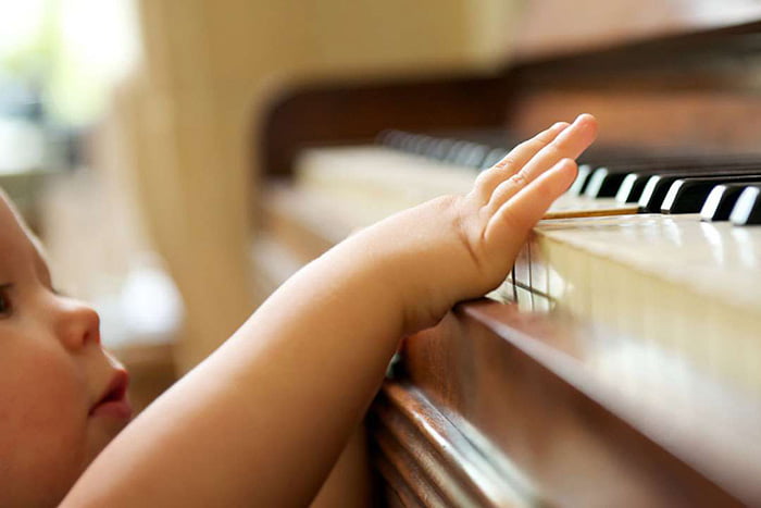 Ребенок нажимает на клавишу пианино