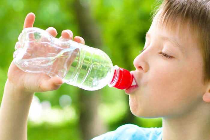 Мальчик пьет воду из бутылки