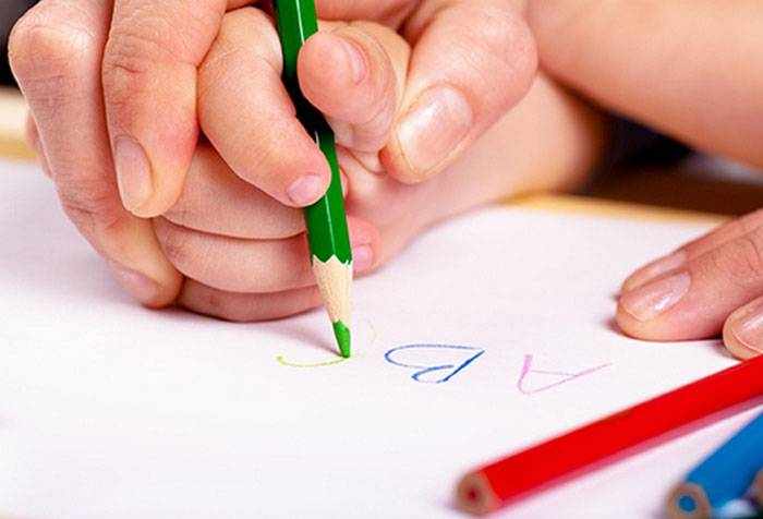 Взрослый учит ребенка писать карандашом