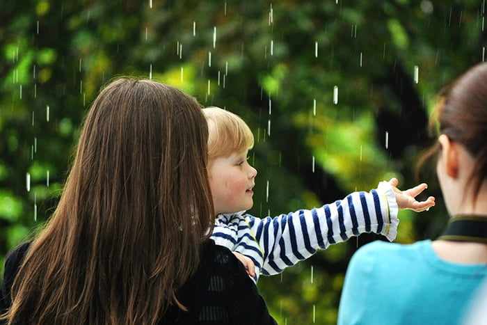 Ребенок под каплями летнего дождя