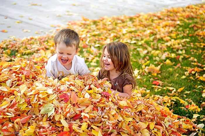 Дети играют в осенних листьях