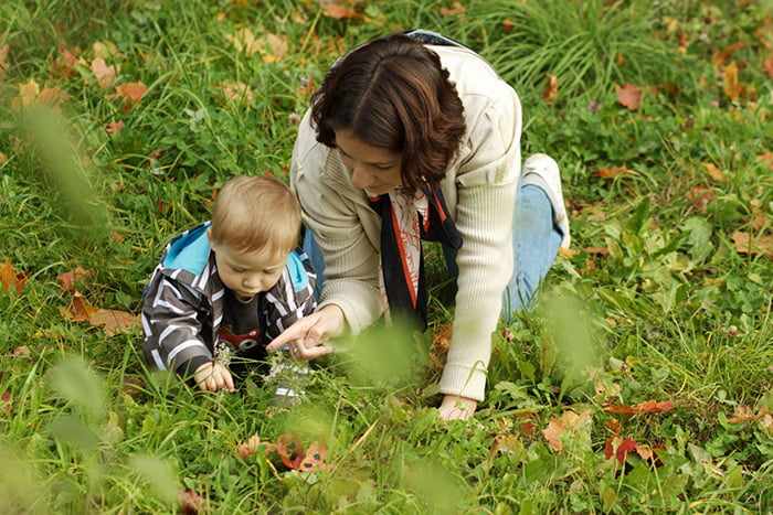 Мама с малышом на прогулке рассматривают растения
