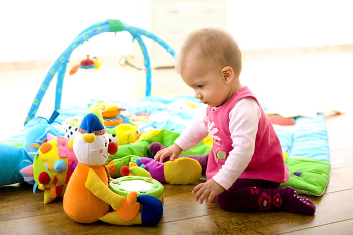 Маленькая девочка играет с мягкими игрушками