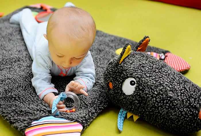 Малыш играет на развивающем коврике