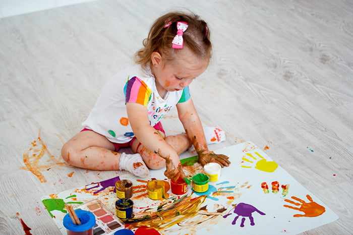 Маленькая девочка рисует пальчиковыми красками