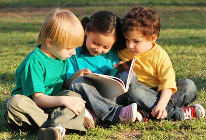 Дети читают книжку на улице