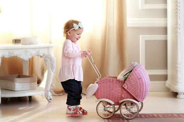 Маленькая девочка с игрушечной коляской 