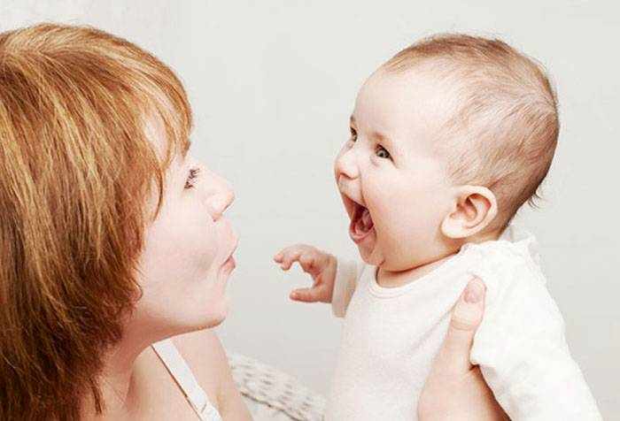 Малыш смеется на руках у мамы