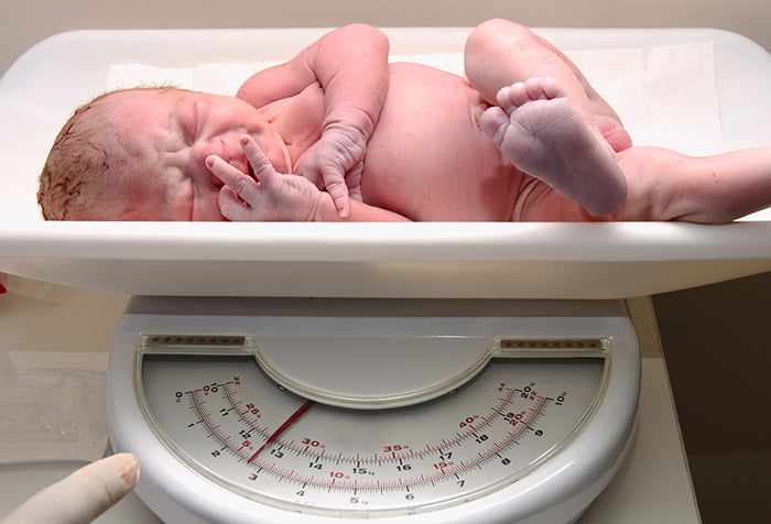 Новорожденный малыш на весах
