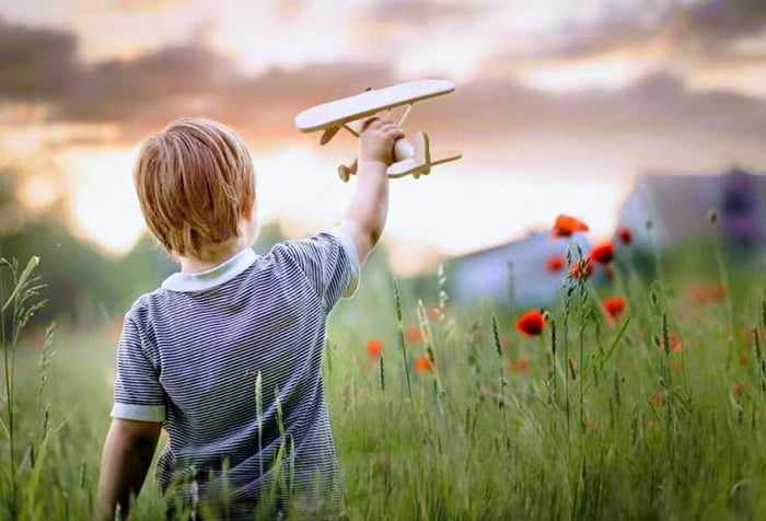 Ребенок играет с деревянным самолетом