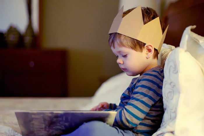 Ребенок в картонной короне читает книжку
