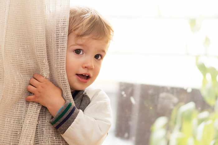 Ребенок прячется за шторой