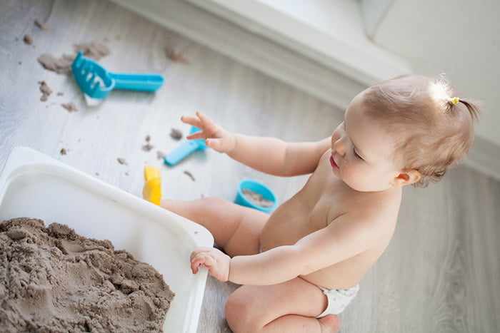 Маленькая девочка играет в домашней песочнице