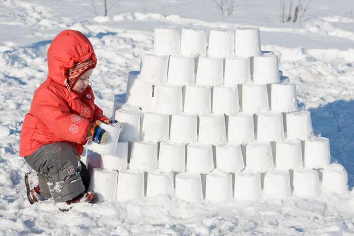 Ребенок строит крепость из снега