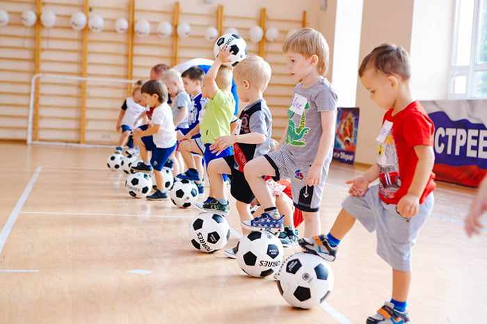 Дети с футбольными мячами на занятии